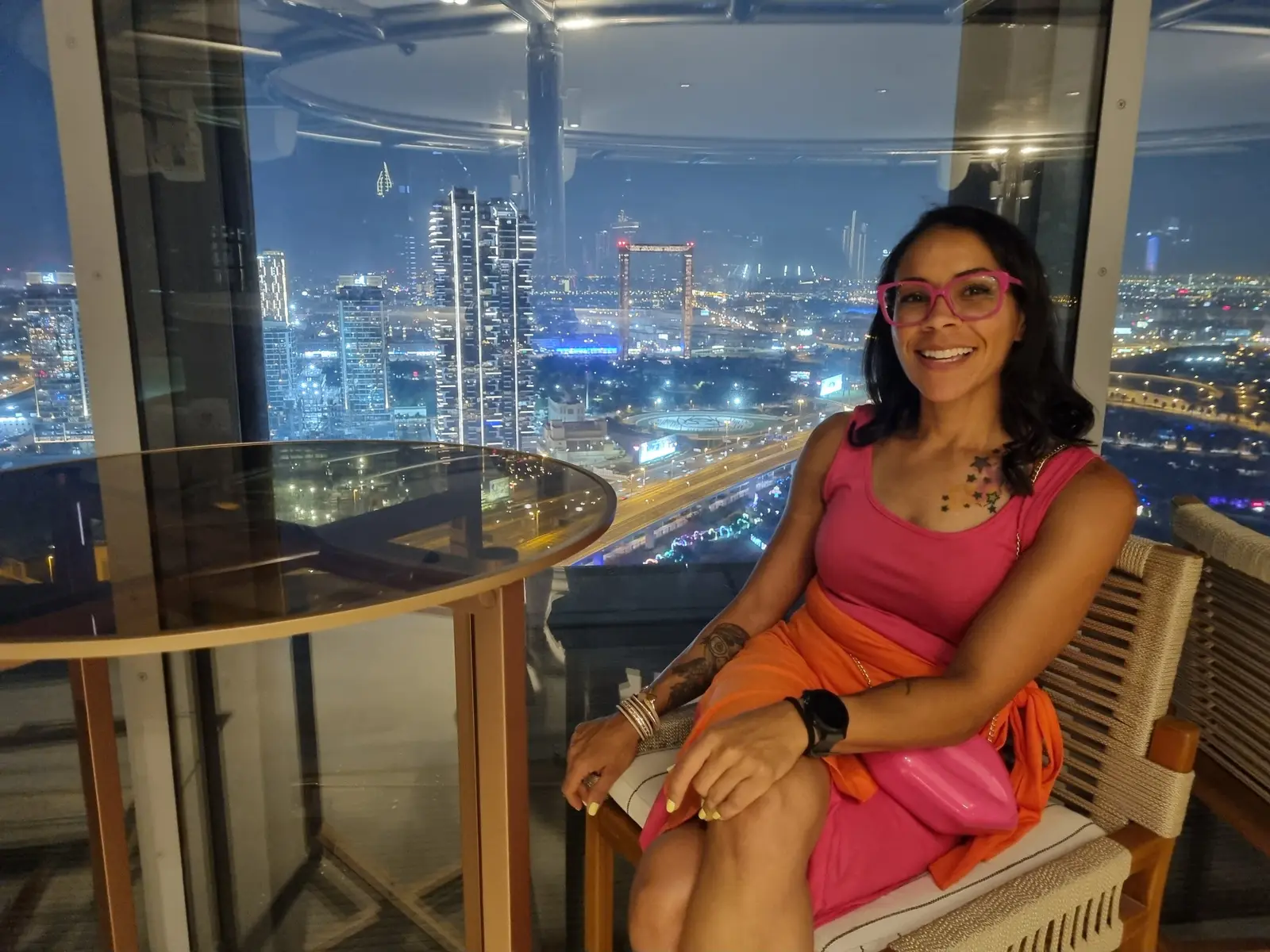 Lisa seated by a window overlooking Dubai at night