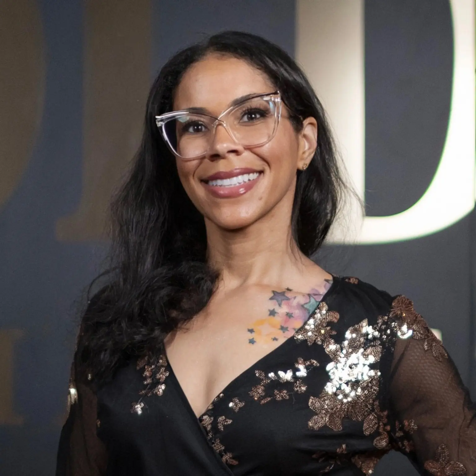 Lisa Michelle smiling in a black and gold dress
